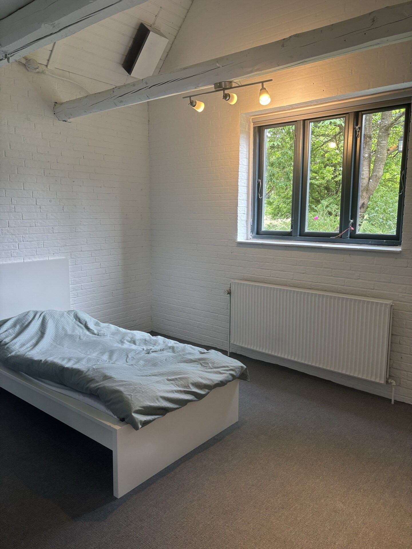 Lille soveværelse med enkeltseng og skrivebord nær trappen